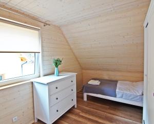 niewielka sypialnia z łóżkiem i oknem w obiekcie Sosnowe Wzgórze w Pasymiu