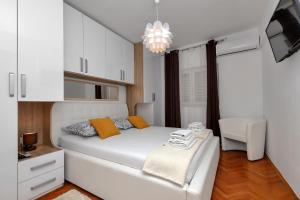sypialnia z białym łóżkiem i białym krzesłem w obiekcie Apartment Sabina w Makarskiej