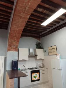 een keuken met witte apparatuur en een bakstenen plafond bij La grotta nel borgo in Roccastrada