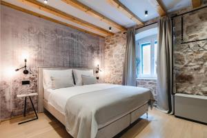 a bedroom with a large bed and a brick wall at Amoretta rooms in Šibenik