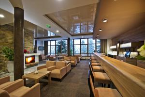a lobby with a bar and chairs and a fireplace at Hotel SOREA URÁN in Tatranská Lomnica