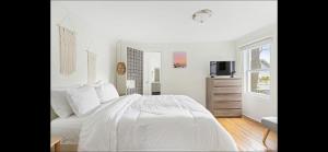 a white bedroom with a bed and a television at The Melrose in Ocean Grove