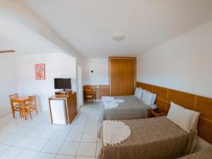 ein Hotelzimmer mit 2 Betten und einem Tisch in der Unterkunft Hotel Recanto dos Pássaros in São Sebastião