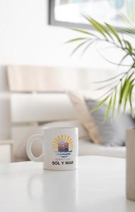 una taza de café sentada en un escritorio junto a una planta en Deptos Sol y Mar en Necochea