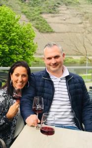 Ein Mann und eine Frau mit Weingläsern. in der Unterkunft Residenz Moselzauber - Ferienwohnungen mit Pool Landschaft in Ernst