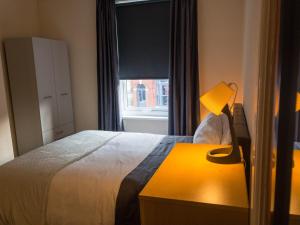 a bedroom with a bed with a lamp and a window at Home Away From Home in Sheffield