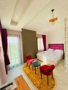 a bedroom with a bed and two red chairs at Luna Mare Resort Mersin in Mersin +104 photos