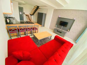 a living room with a red couch and a kitchen at Vm Resort Otel Mersin in Mersin