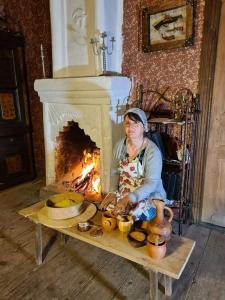 a woman sitting on a table in front of a fireplace at Guest House Balda in Martvili