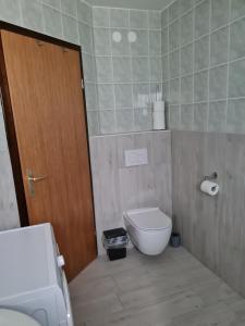 ein Badezimmer mit einem WC und einer Holztür in der Unterkunft Apartma Juteršek 2+2 in Libeliče