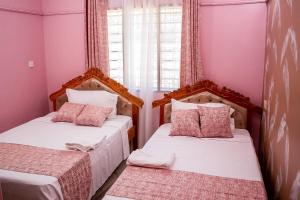 2 łóżka w małym pokoju z różowymi ścianami w obiekcie Dondoo's Paradise- Perfect Vacation Home w mieście Kilifi