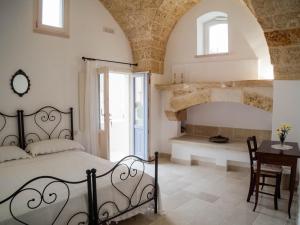 a bedroom with a bed and a table and a fireplace at Asylum Amicorum Bed & Breakfast in Gagliano del Capo