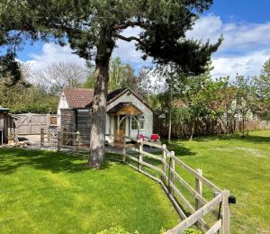 a house with a fence and a tree at Field's Edge in Swinderby