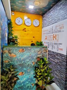 Zimmer mit Uhren an einer gelben Wand und einem Aquarium in der Unterkunft Atithistay Thane in Thane
