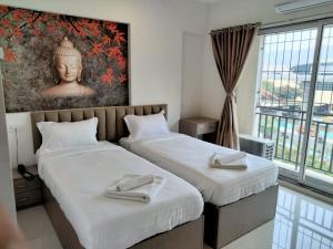 2 Betten in einem Zimmer mit einem großen Fenster in der Unterkunft Atithistay Thane in Thane