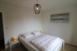 un letto bianco in una camera da letto con lampada di Noble dune a Oostduinkerke