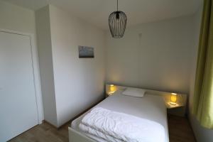 una piccola camera da letto con un letto bianco con luci di Noble dune a Oostduinkerke