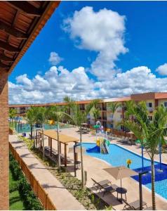 a pool at a resort with tables and palm trees at Ondas Praia Resort in Porto Seguro