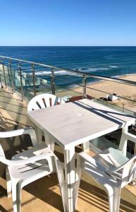 una mesa blanca y sillas en un balcón con vistas al océano en BEACH APARTMENT no 17, en Saints Constantine and Helena