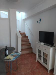 sala de estar con TV, mesa y escaleras en La Motilla en Barbate