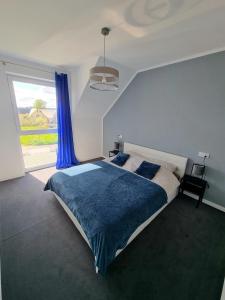 a bedroom with a bed with a blue blanket and a window at Domek pod świerkami - "Apartamenty świerkowe" in Kudowa-Zdrój