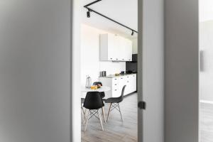 a white kitchen with a table and chairs through a door at Apartament BlueBay in Puck