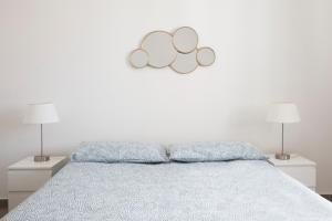 a white bedroom with a bed with two lamps at GLBapartments in Capo dʼOrlando