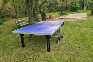 een tafeltennistafel in het gras met een bank bij Maison avec rivière, piscine, SPA, SAUNA Infrarouge,terrain boules, ping-pong, volley et Badminton in Sainte-Tulle