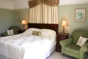 a bedroom with a white bed and two chairs at Stoneborough House B&B in Budleigh Salterton
