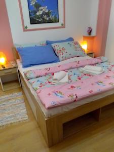 ein Bett mit einer rosa Bettdecke und Kissen darauf in der Unterkunft Studio apartman Šafarić in Sveti Martin na Muri