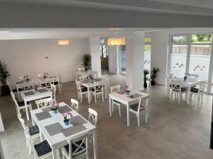 a restaurant with white tables and chairs and windows at Pensiunea Mara in Techirghiol