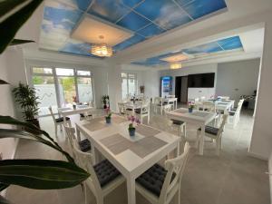 a dining room with white tables and white chairs at Pensiunea Mara in Techirghiol
