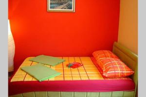 a bed with two pillows and a red wall at Apartman Budva Ivana in Budva