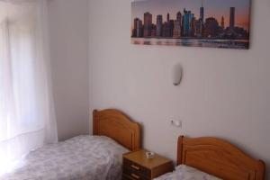 a bedroom with two beds and a picture of a city at Apartamento al lado de la playa con parking y jardín in Platja  d'Aro