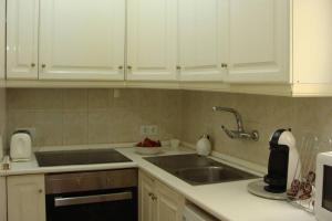 a kitchen with white cabinets and a sink at Apartamento al lado de la playa con parking y jardín in Platja  d'Aro