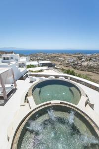 a swimming pool on a patio with the ocean in the background at Sea & Stone Residence Mykonos in Platis Yialos Mykonos