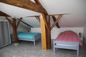 two beds in a room with wooden beams at LE Gîte DE LA GRANGE DE BROUSTIC in Lahosse