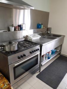 uma cozinha com um fogão de aço inoxidável e um lavatório em LE Gîte DE LA GRANGE DE BROUSTIC em Lahosse