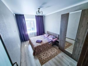 um pequeno quarto com uma cama e um espelho em Элитные апартаменты в Центре em Semei