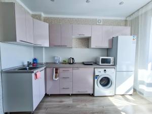 cocina con nevera y lavadora en Элитные апартаменты в Центре, en Semey