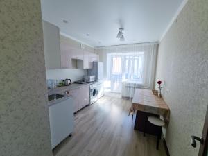 uma cozinha com electrodomésticos brancos e piso em madeira em Элитные апартаменты в Центре em Semei