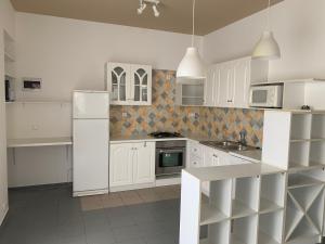 una cocina blanca con armarios y electrodomésticos blancos en Centrum nyaraló Vonyarcvashegy, en Vonyarcvashegy