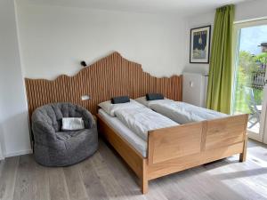 um quarto com uma cama, uma cadeira e uma janela em BÄRENALP Ferienwohnen em Garmisch-Partenkirchen