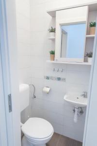 a white bathroom with a toilet and a sink at Apartments Dzeki in Split