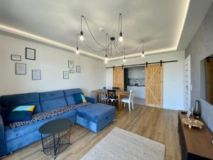 a living room with a blue couch and a dining room at SunRise Apartament in Lublin