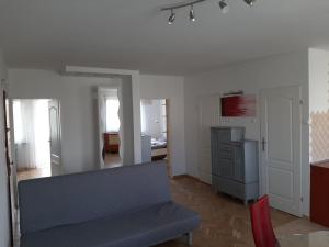 een woonkamer met een blauwe bank en een keuken bij Apartament Bella in Bolesławiec