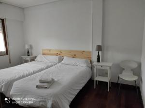 カサラレイナにあるCasa del Abuelo - San Lorenzoの白いベッド1台(木製ヘッドボード付)が備わるベッドルーム1室が備わります。
