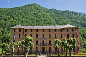 un grande edificio con alberi di fronte a una montagna di NOUVEAU ! MAGNIFIQUE T2 FACE AUX THERMES ad Aulus-les-Bains