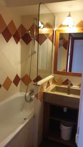 a bathroom with a tub and a sink and a mirror at Appartement Alpe d'huez in LʼHuez