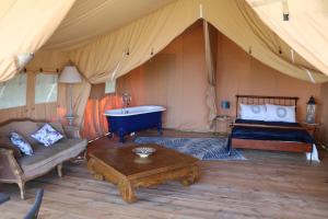Una habitación con cama y bañera en una tienda en Les Toiles de La Tortillère tentes luxes safari lodge glamping insolite, en Marçay
